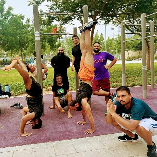 Agish Kavithil with group of people doing movement like headstand